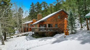 Een houten chalet met balkon, omringd door sneeuw en bomen.