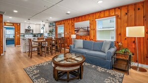 A living room with a sofa, coffee table, and dining area with chairs. - NEW LISTING! 15th St Beach Retreat #2 - 2 Bed/1 Bath Waterfront w/ Dock (Ocean City)