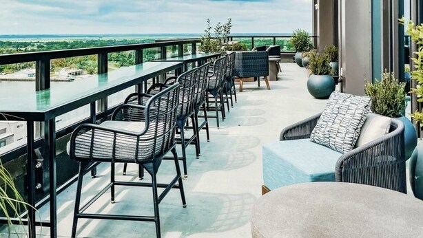 Une terrasse sur le toit, avec des sièges en plein air, une table en verre et une vue sur le paysage.
