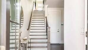 Un escalier menant à une porte, avec une petite table et une porte vitrée sur la gauche.