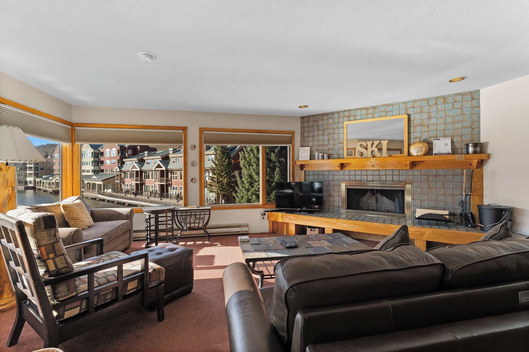 A living room with a fireplace, a television, and a view of a canal.