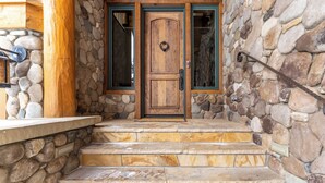 A stone-clad entrance with a wooden door and steps leading up to a porch. - 140 Goldenrod Circle by Summit County Mountain Retreats (Keystone)