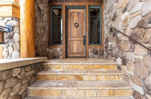 A stone-clad entrance with a wooden door and a metal gate.