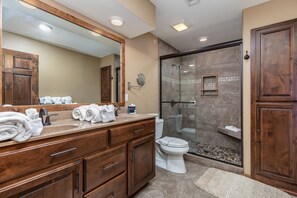 A bathroom with a wooden vanity, a large mirror, a glass shower enclosure, and a white toilet. - 3BR+Loft Village At Indian Point 1406 near SDC -Free Tickets up to $500 Value (Branson)