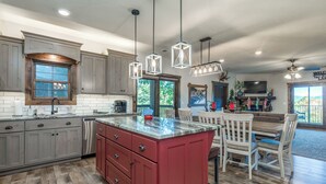 A spacious kitchen with a large island, wooden cabinets, and pendant lighting.