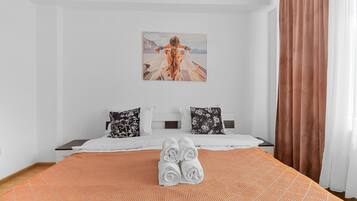 A hotel room with a bed, pillows, a painting, and a window with curtains.