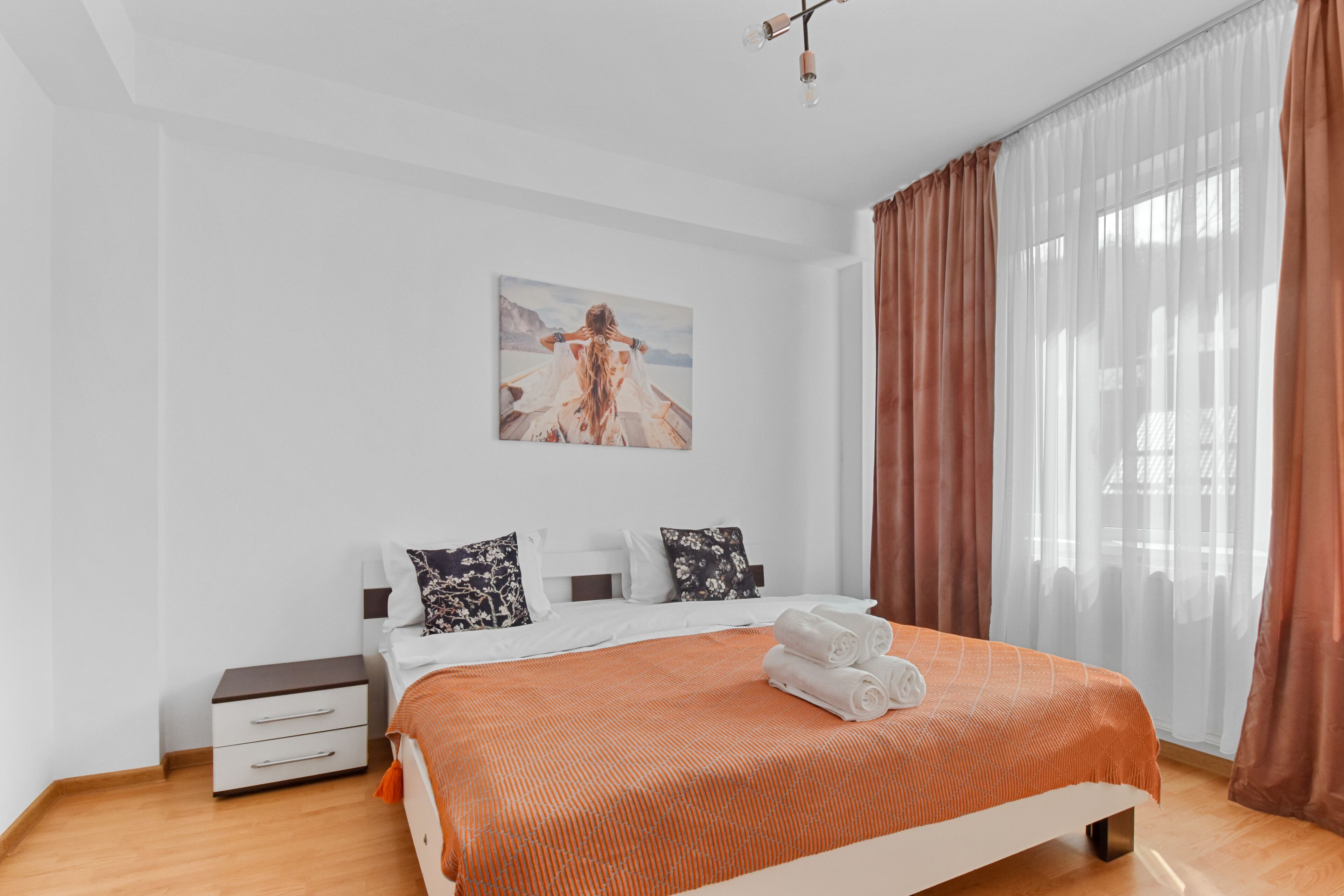 A modern bedroom with a large bed, a nightstand, and a painting on the wall.