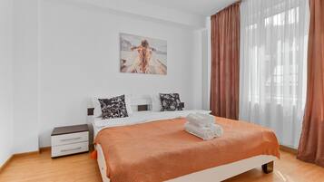 A modern bedroom with a large bed, a nightstand, and a painting on the wall.