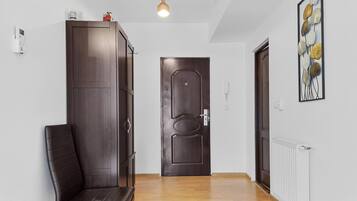 Un couloir avec une armoire en bois sombre, un banc, une porte et un radiateur.