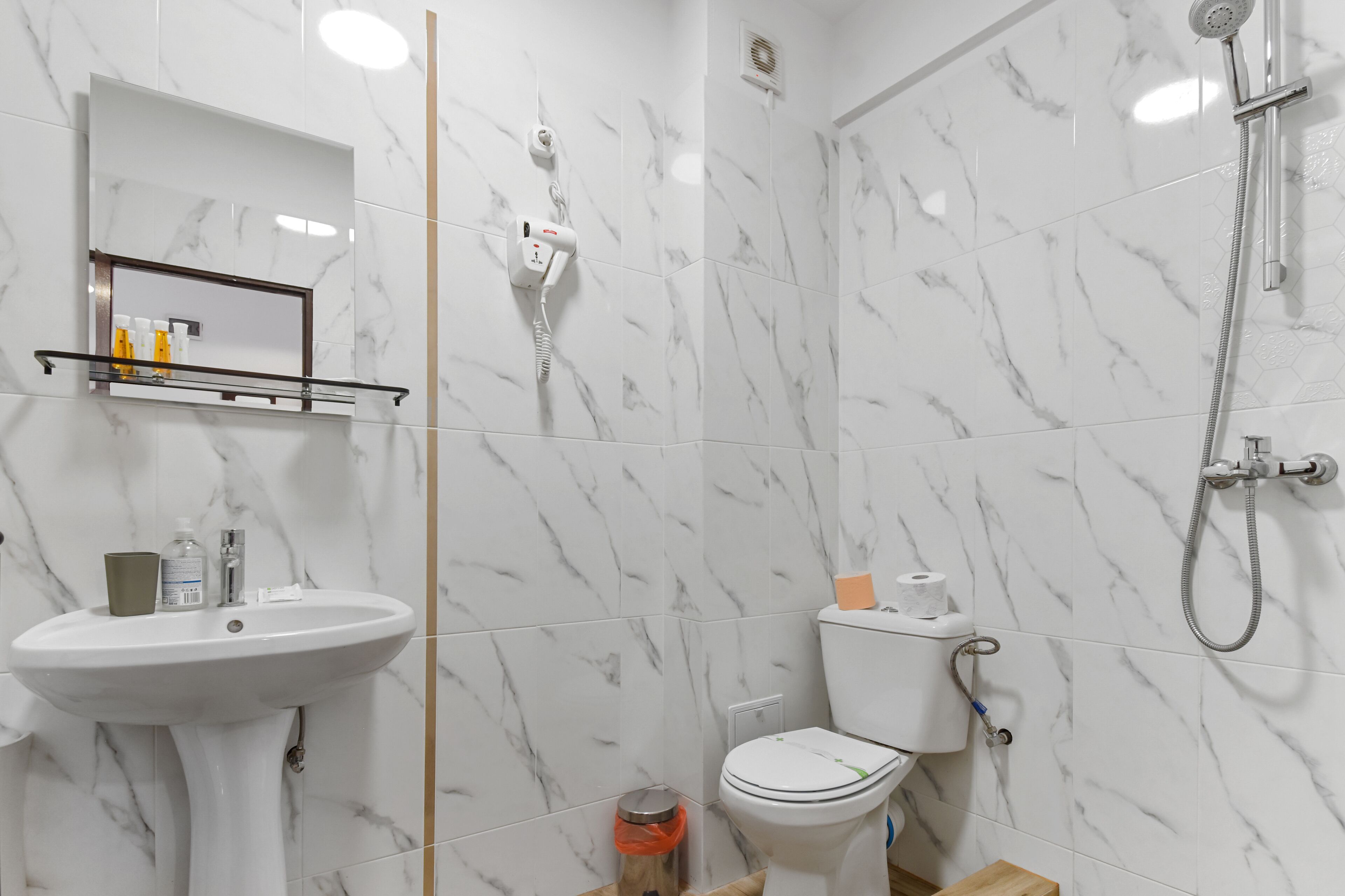 A bathroom with a white sink, a mirror, a toilet, and a shower.