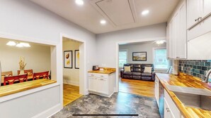 A modern kitchen with white cabinets, a wooden countertop, and a dining area with a wooden table and chairs. - Cheerful Four Bedroom home conveniently located (Augusta)
