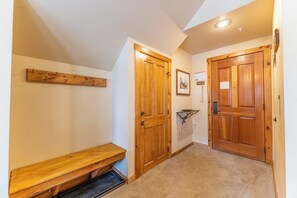 A hallway with wooden doors, a bench, and a small shelf.