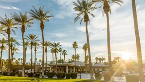 A hotel with a well-maintained lawn, palm trees, and a parking area. - COACHELLA Marrriott Desert Spring Villa 1, Kitchen, Access to Resort (Palm Desert)
