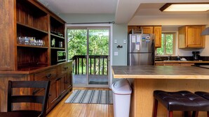 A kitchen with wooden cabinets, a stainless steel refrigerator, a large island, and a sliding glass door leading to a balcony. - Villamont #6916 by Summit County Mountain Retreats (Silverthorne)