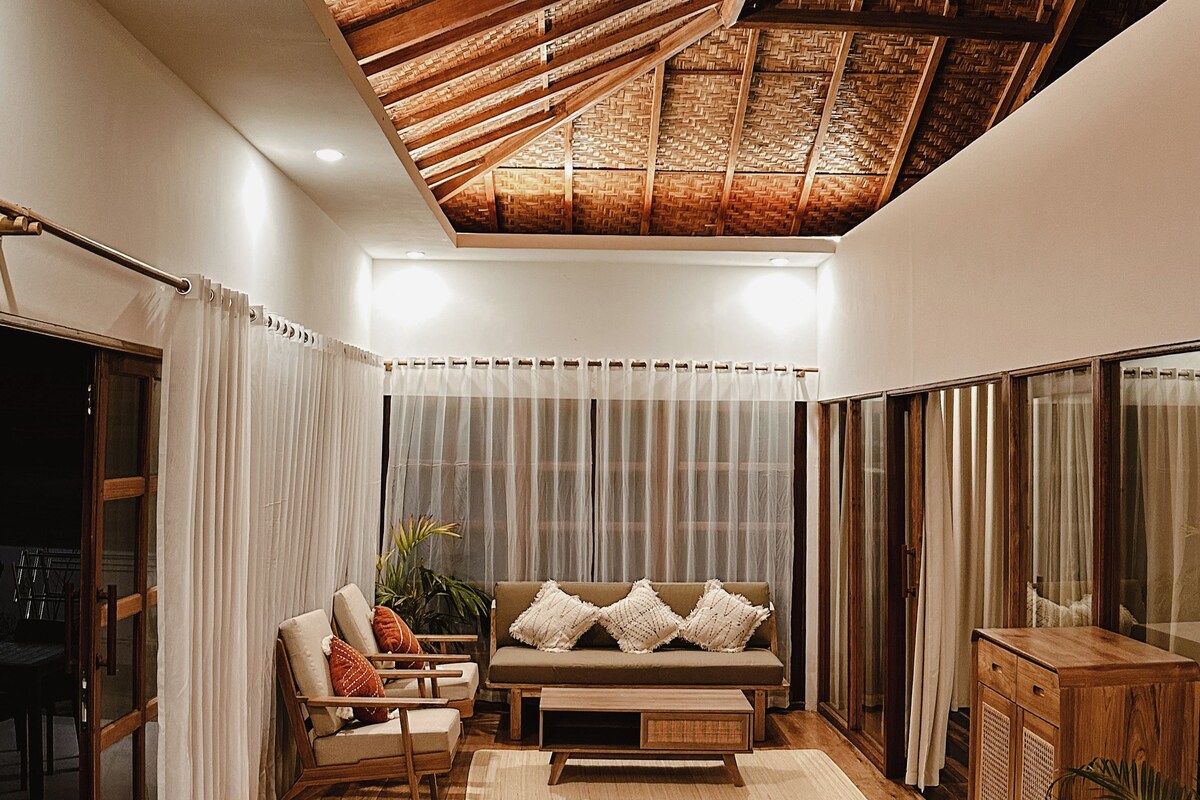 A cozy living room with wooden flooring, a sofa, two armchairs, and a coffee table.