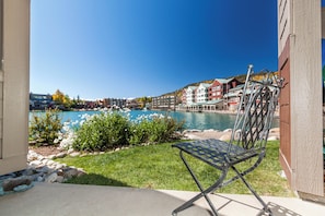 Un patio con una silla metálica, una piscina y edificios al fondo.