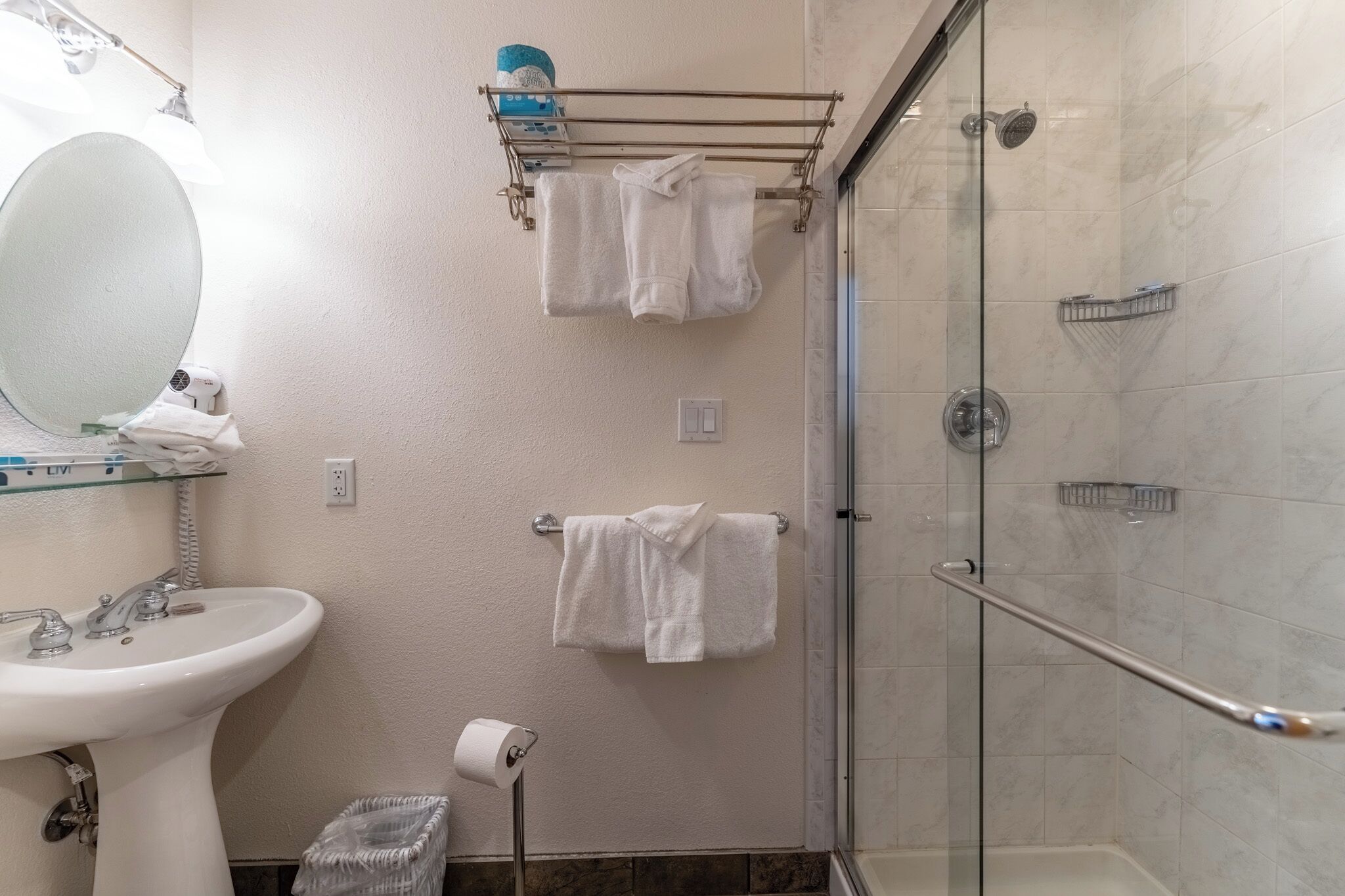 A bathroom with a sink, mirror, towel rack, and glass shower enclosure.