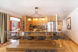 A spacious kitchen with a central island, bar stools, and a hanging light fixture.