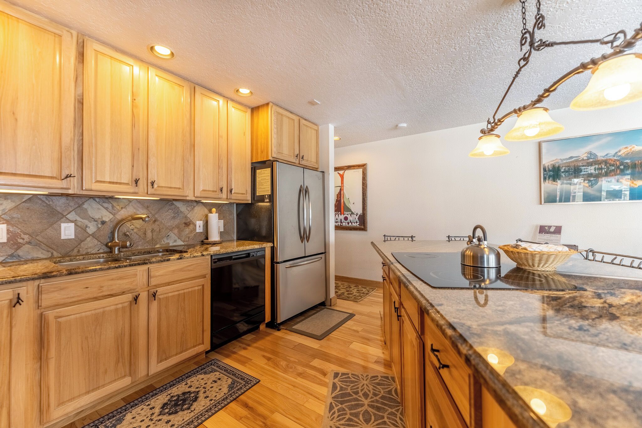 A modern kitchen with wooden cabinets, stainless steel appliances, and a granite countertop.