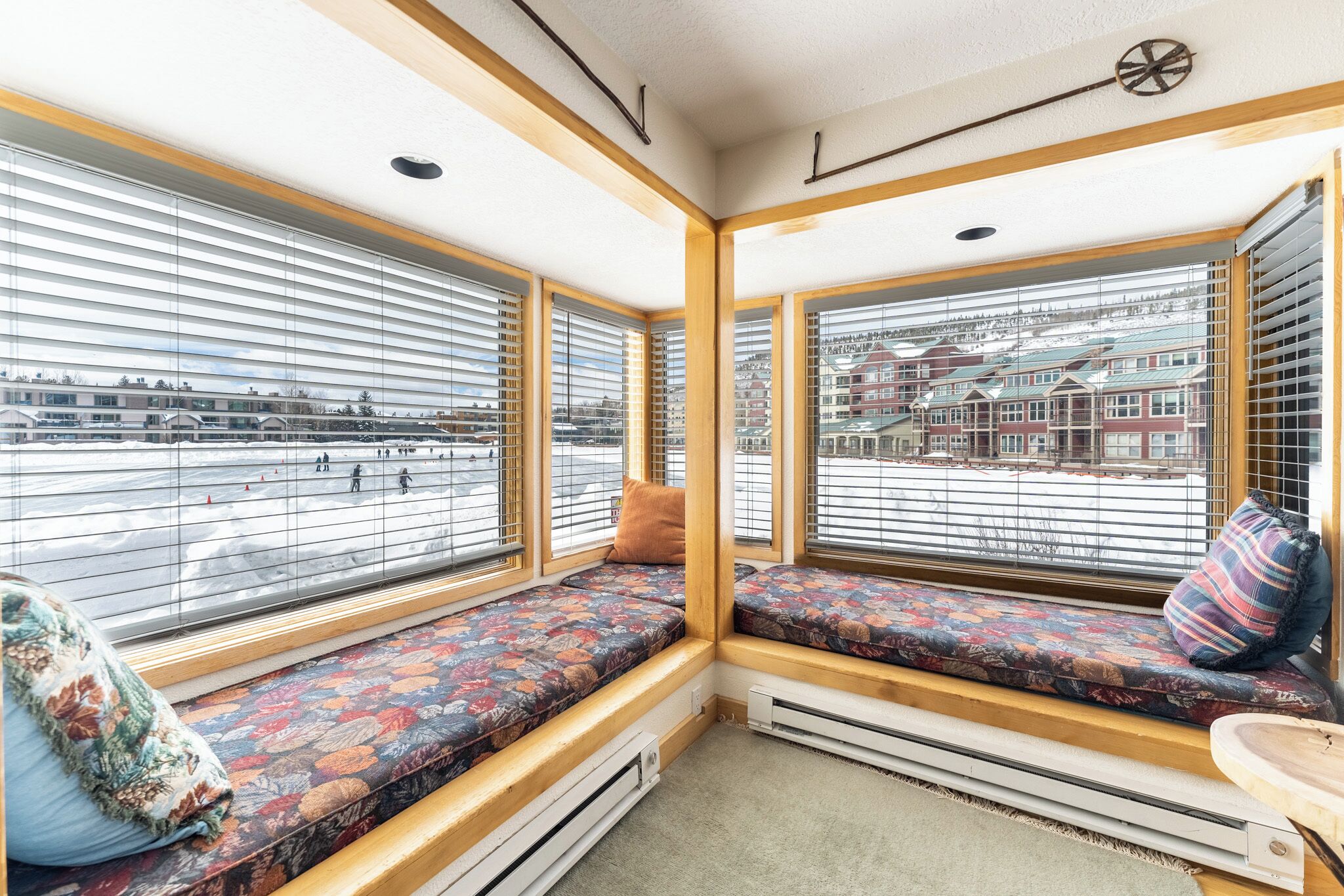 A corner room with a built-in bench and large windows with blinds, offering a view of a snowy street.