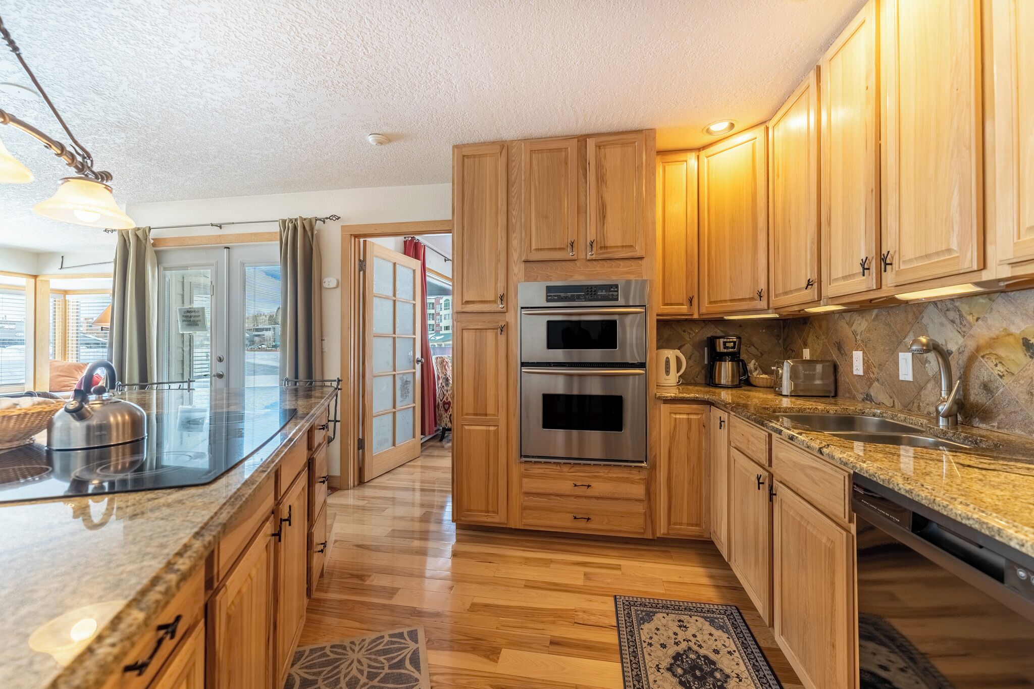 A modern kitchen with wooden cabinets, stainless steel appliances, and a granite countertop.