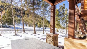 En träveranda med en stenkant och en bänk, med utsikt över ett snötäckt landskap med träd.