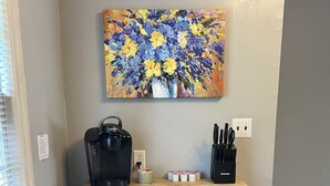 A kitchenette with a coffee maker, knife block, and a painting of flowers on the wall. - Close to Downtown-Primary on Main-Fast Internet (Greensboro)