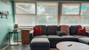 A living room with a sectional sofa, a round coffee table, and a patterned rug. - Close to Downtown-Primary on Main-Fast Internet (Greensboro)