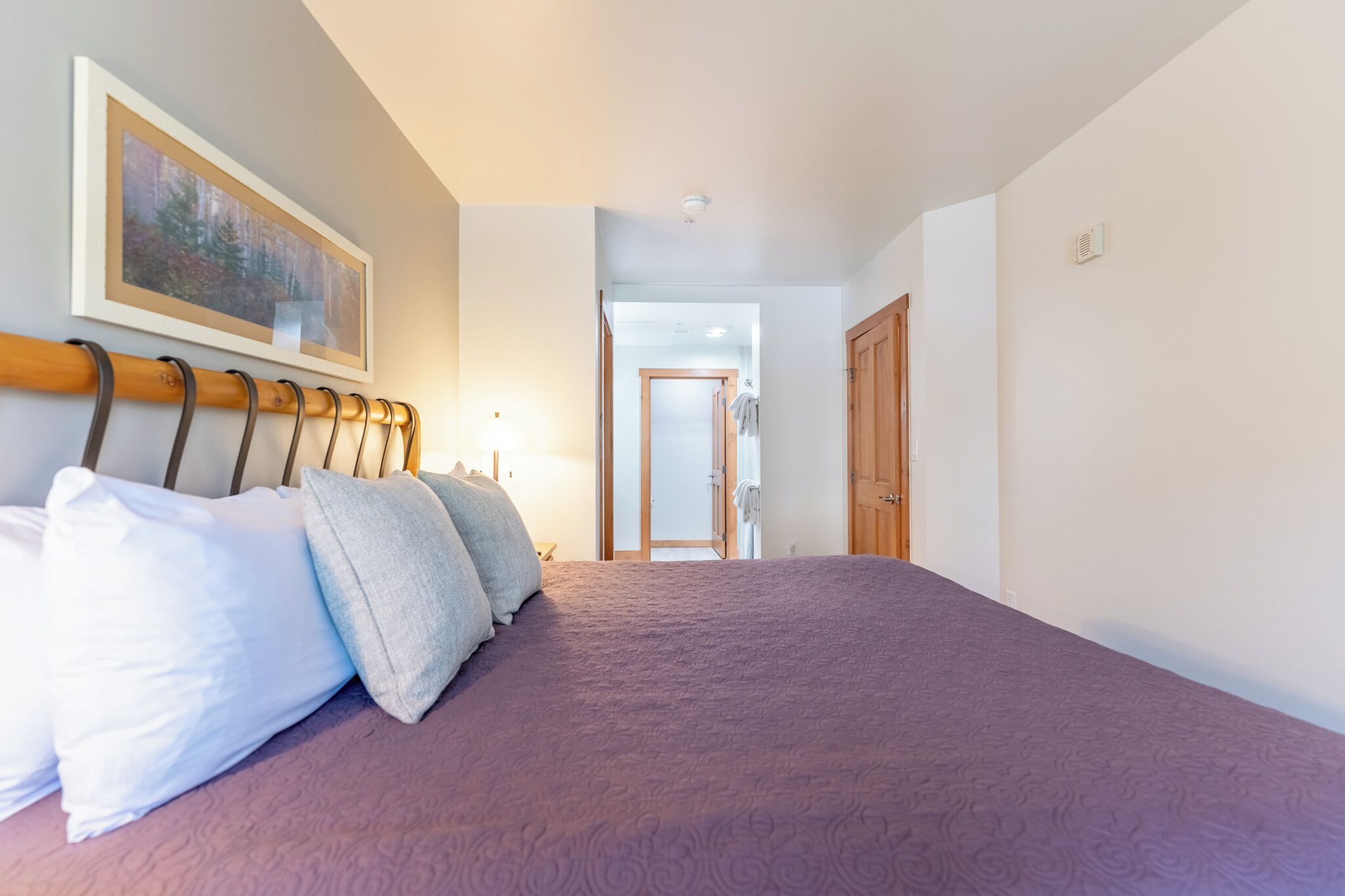 Un dormitorio con una cama grande, un cabecero de madera y un cuadro enmarcado en la pared.
