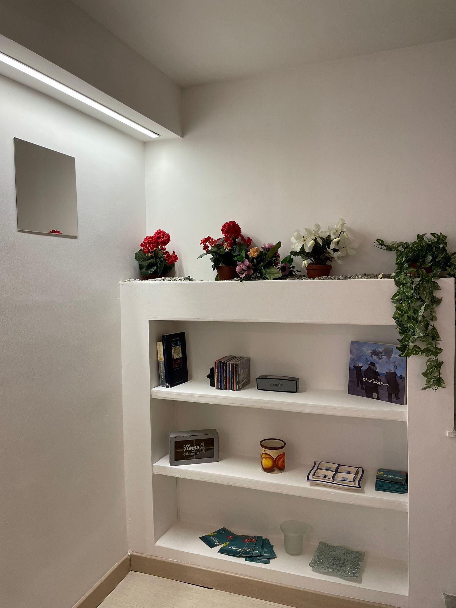 Ein weißes Regal mit Büchern, einer kleinen Schachtel und einem gerahmten Bild.