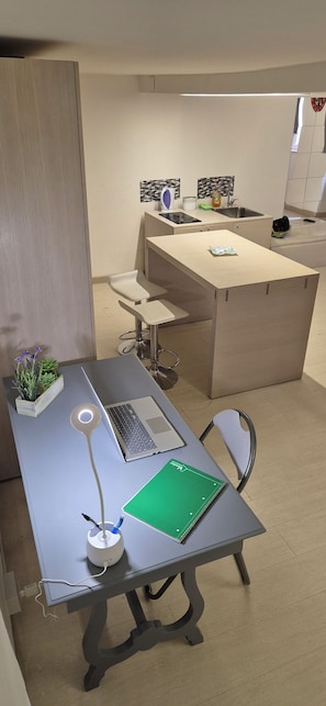 A modern office space with a desk, chair, laptop, notepad, pen, and a small plant. - Maximum Loft's Nest (Palermo)