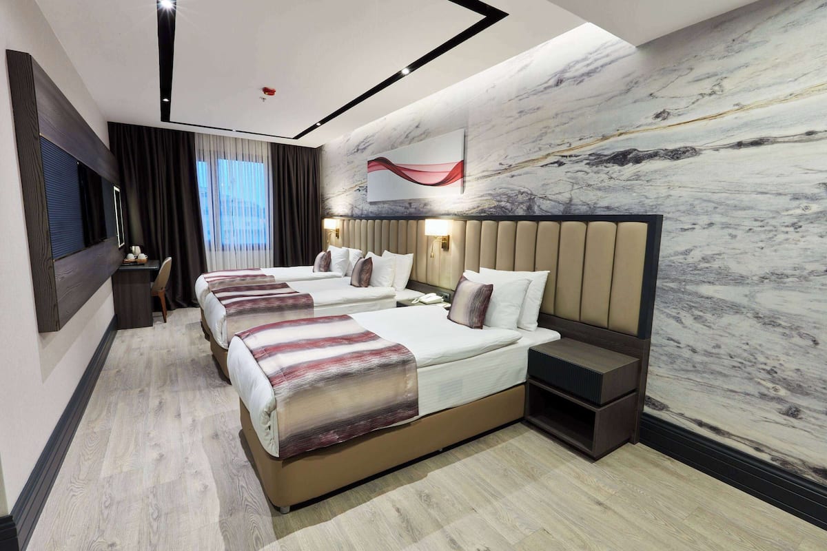 Una habitación de hotel con una cama grande, un escritorio y un televisor.