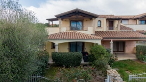 A two-story house with a tiled roof, a covered porch, and a well-maintained garden. - Casa Delle Ginestre by Wonderful Italy (Olbia)