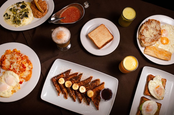 A table with various breakfast dishes including toast, eggs, and a plate of French toast with bananas.