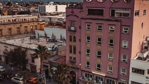 A multi-story building with a pink facade, a balcony, and a sign that reads "EDIFICIO OBRAS."