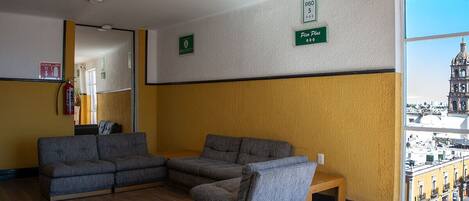 A room with a sofa set, a small table, and a window with a city view.