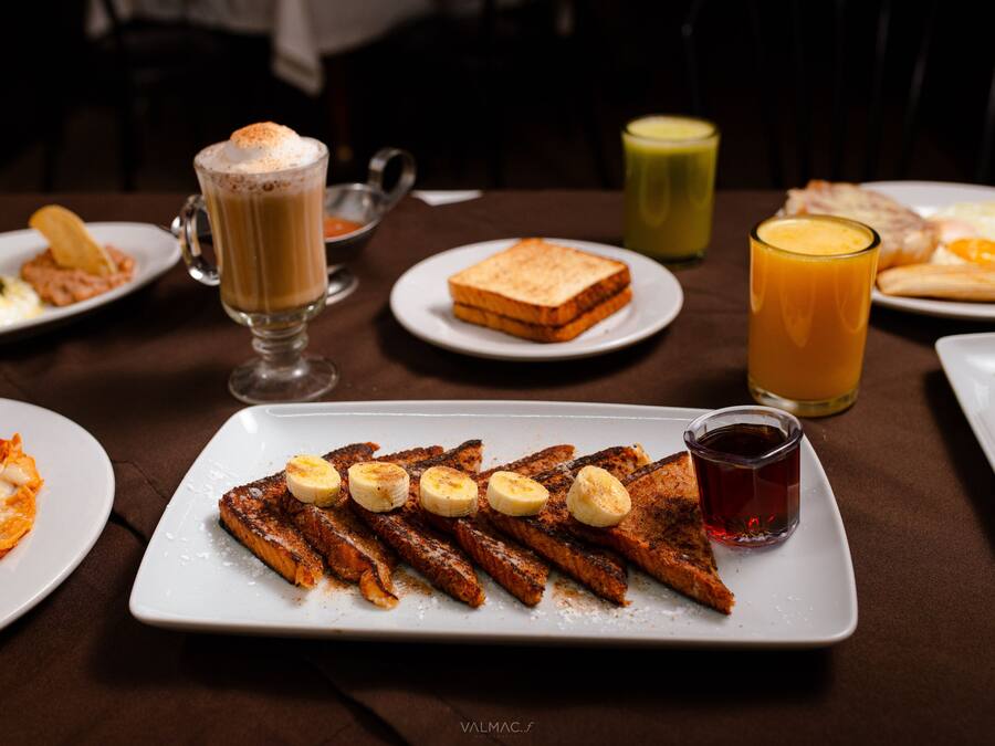 A breakfast setting with various dishes including toast, bacon, and a fruit-topped plate.