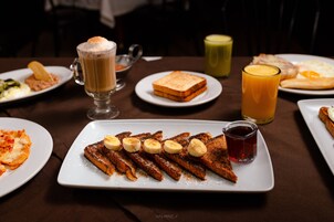 A breakfast setting with various dishes including toast, bacon, and a fruit-topped plate.