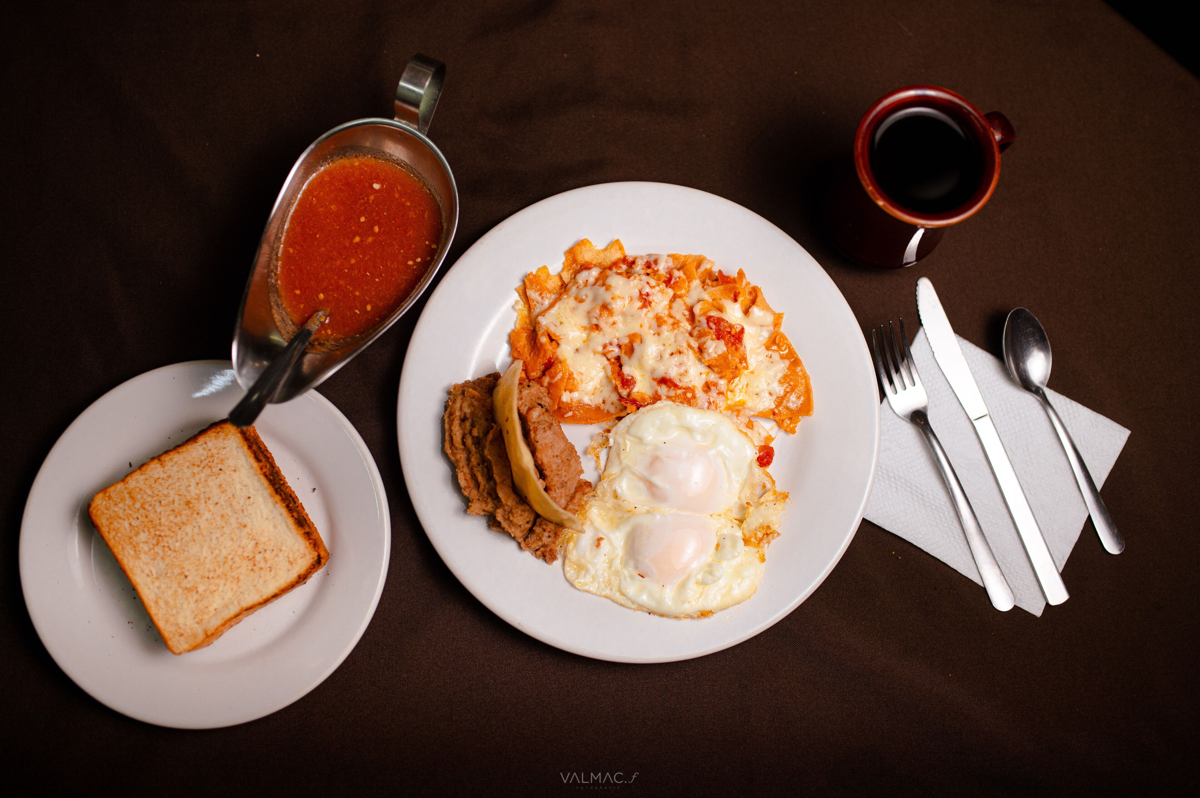 A plate with eggs, toast, and a bowl of tomato sauce.