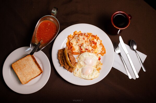 Un plato con huevos, tostadas y un tazón de salsa de tomate.