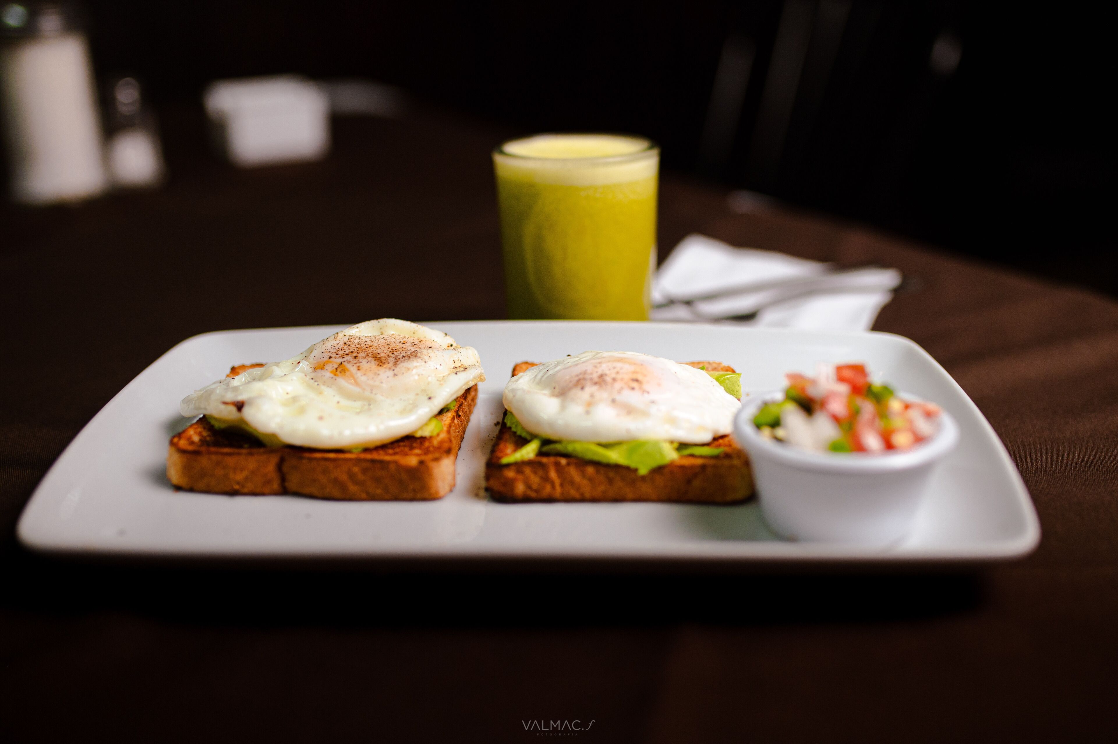 A plate with two open-faced sandwiches, a green smoothie, and a small bowl of salad.