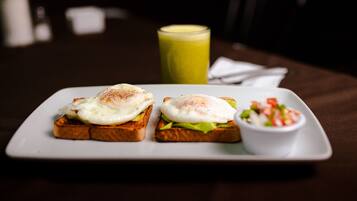 Un plato con dos sándwiches abiertos, un batido verde y un pequeño bol de ensalada.