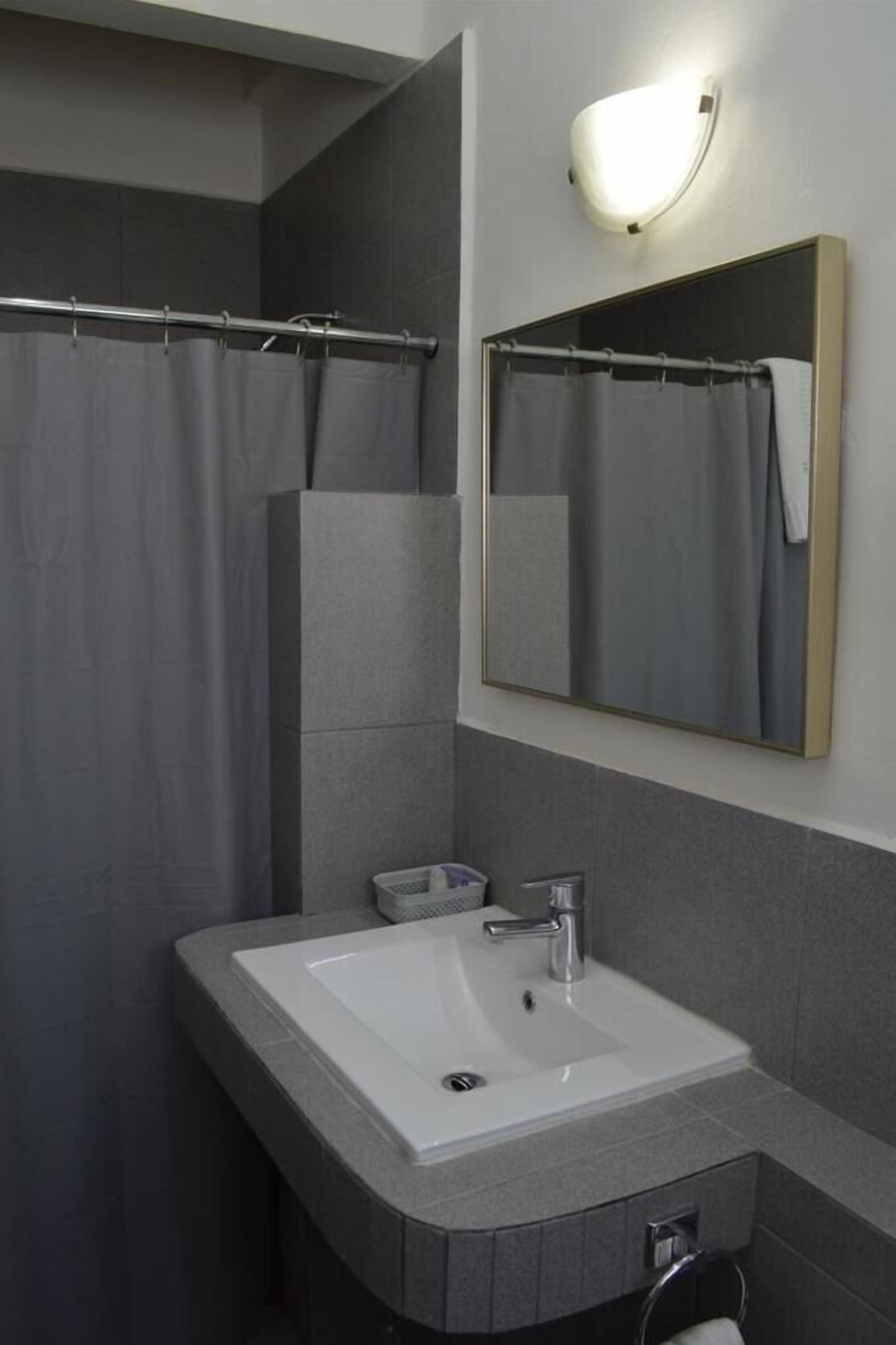 Een badkamer met een witte wastafel, een spiegel en een douchegordijn.
