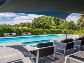 A pool area with lounge chairs and a covered seating area.