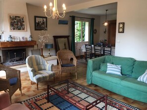 A cozy living room with a fireplace, a dining area, and a green sofa.