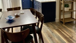 A modern kitchen with dark blue cabinets, a white refrigerator, and a wooden dining table with chairs. - Relax in Ocean Ridge-Near Beach (Boynton Beach)