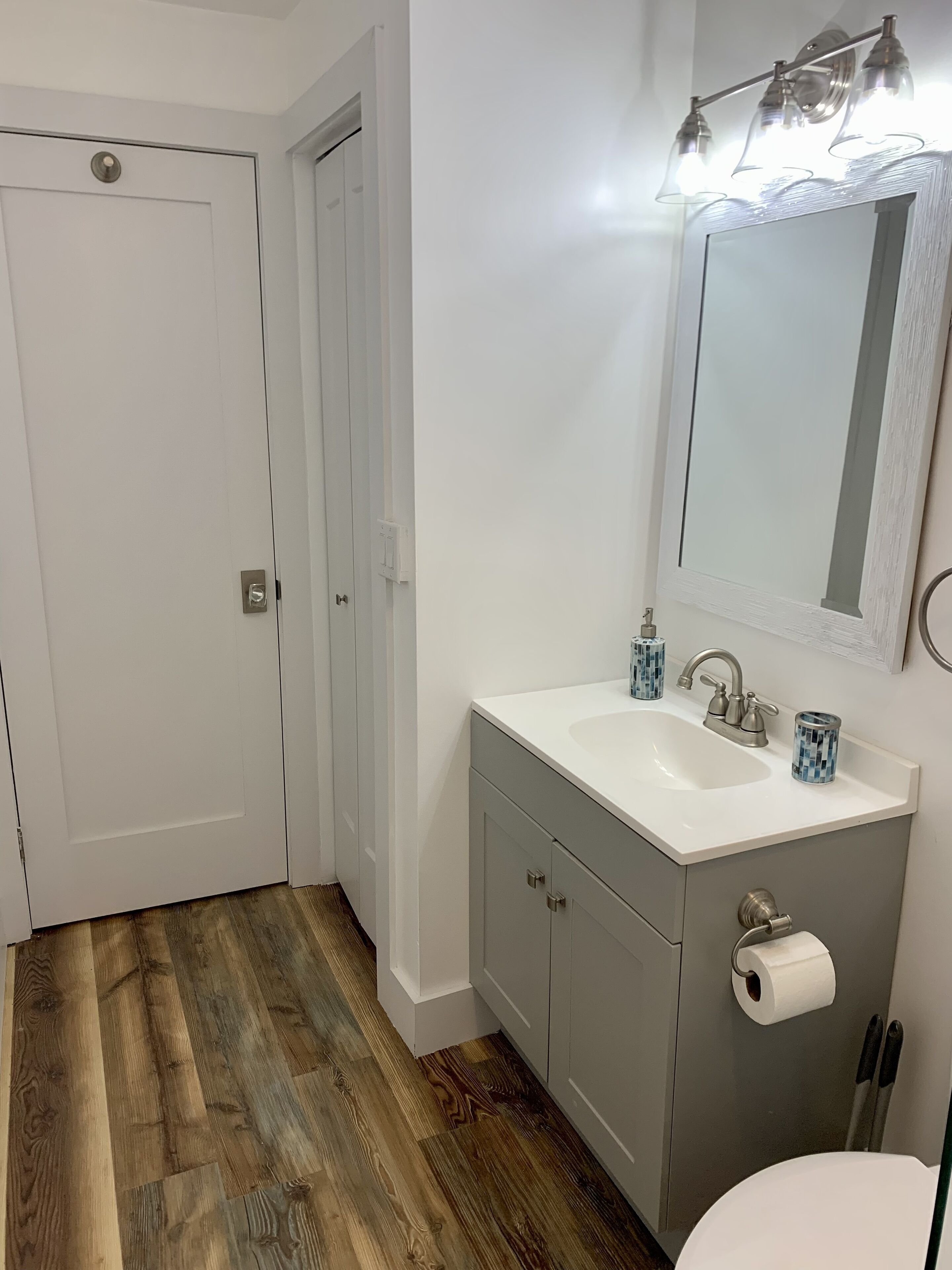 Un bagno con un lavandino bianco, uno specchio e un water.