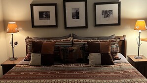 A bedroom with a large bed, two bedside tables, and three framed pictures on the wall.