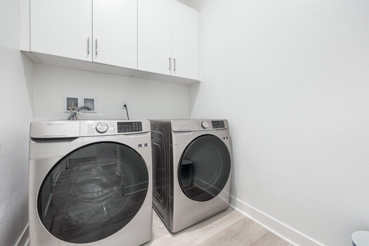 A laundry room with two front-loading washing machines and a cabinet above.
