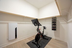 Ein Zimmer mit einem stationären Fahrrad, einem Schuhregal und einer weißen Wand.
